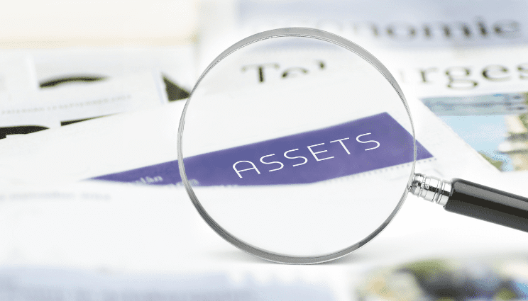 Magnifying glass over the word Assets on financial documents.