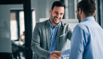 Two business professionals shaking hands in an office.
