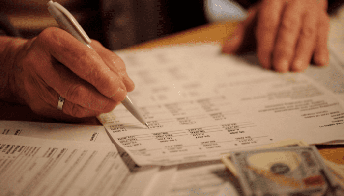 Business owner reviewing financial documents with cash on the desk.
